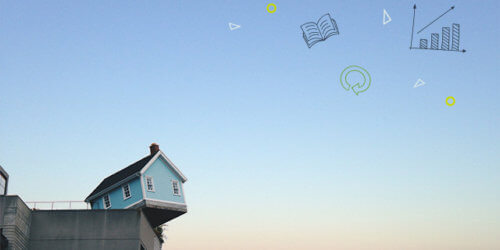 Fotografi på ett litet blått hus som står på kanten av en betongbyggnads tak mot en ljus morgonhimmel.